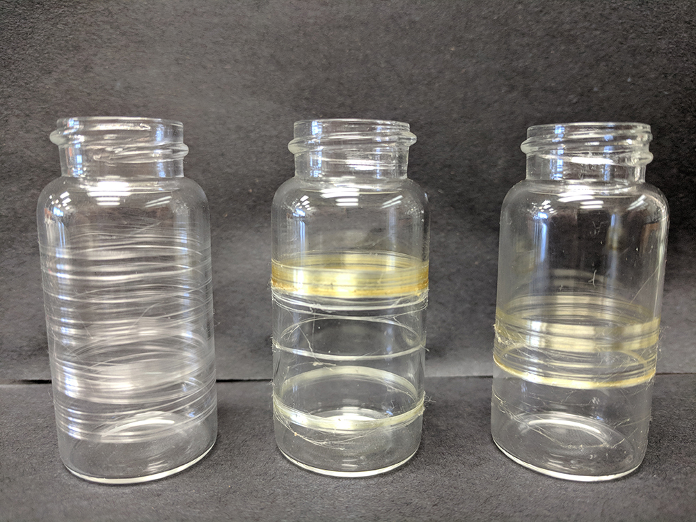 A picture of 3 glass vials wrapped in silk. Some of the silk is bright yellow.